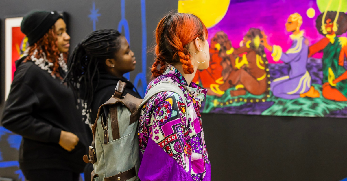 Three students admiring a colourful piece of art.