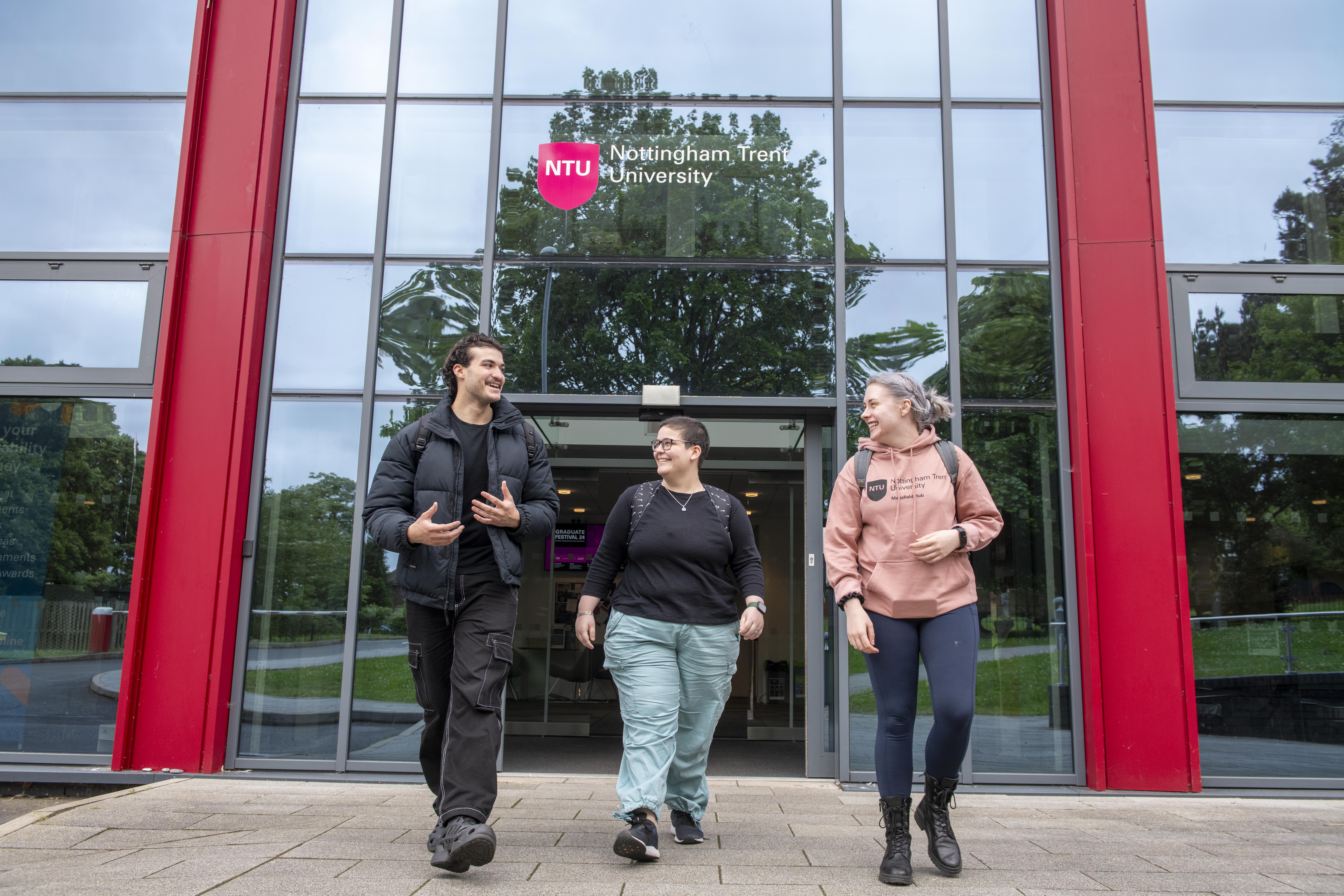 Three students walking happily out of the MUC building at NTU Mansfield.